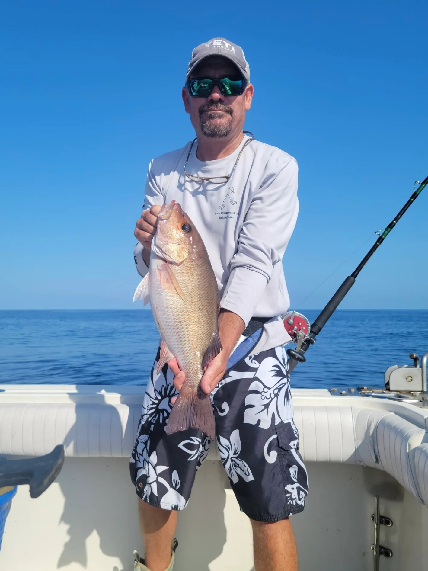 Captain Cuda holding a snapper on a Gulf fishing charter aboard Phat Kat