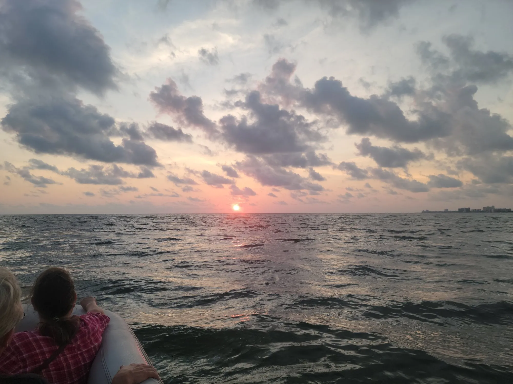 Guests watching a pink Gulf sunset from the deck of Phat Kat