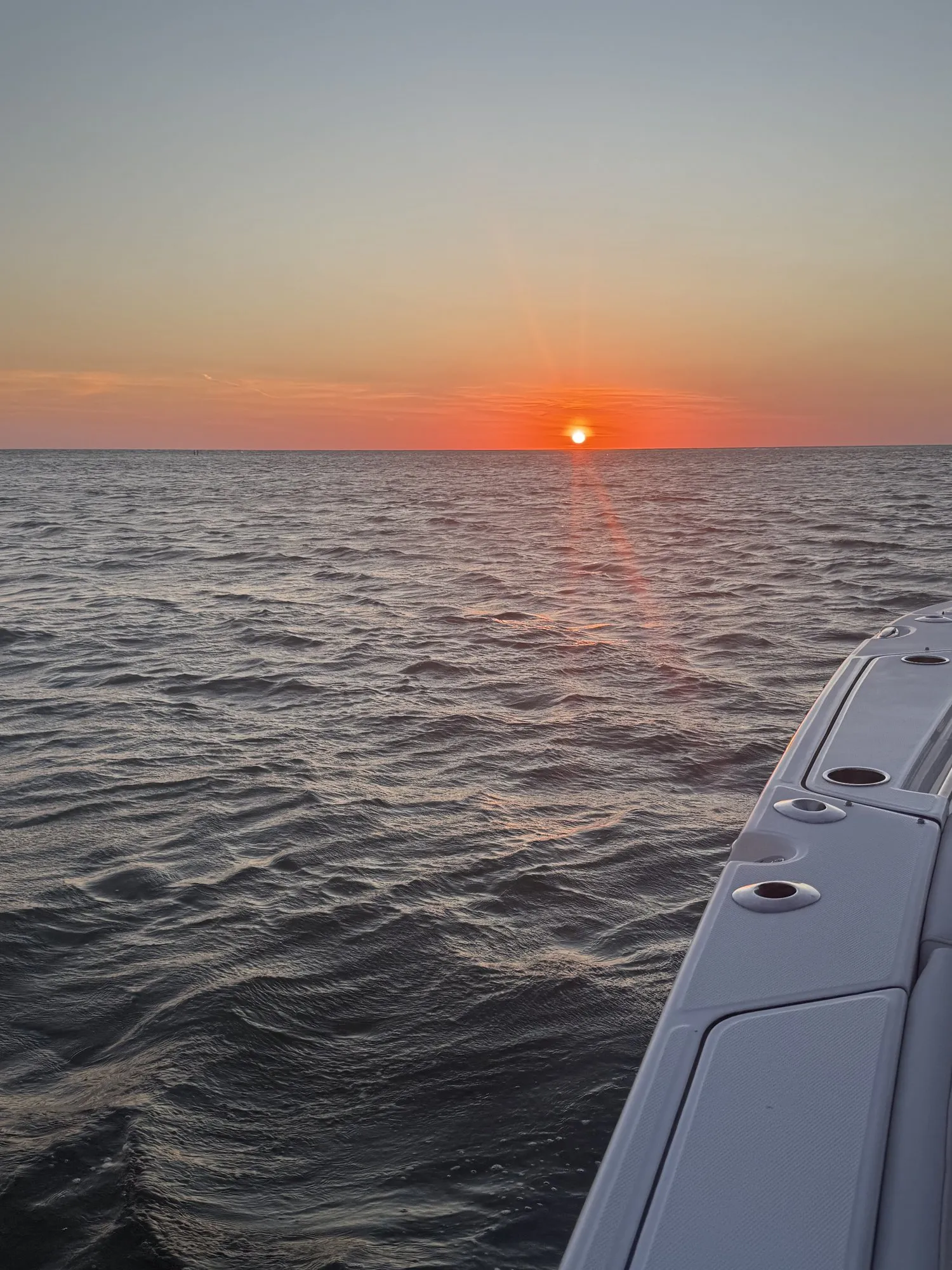 Orange sun setting over the Gulf past the gunwale of Phat Kat