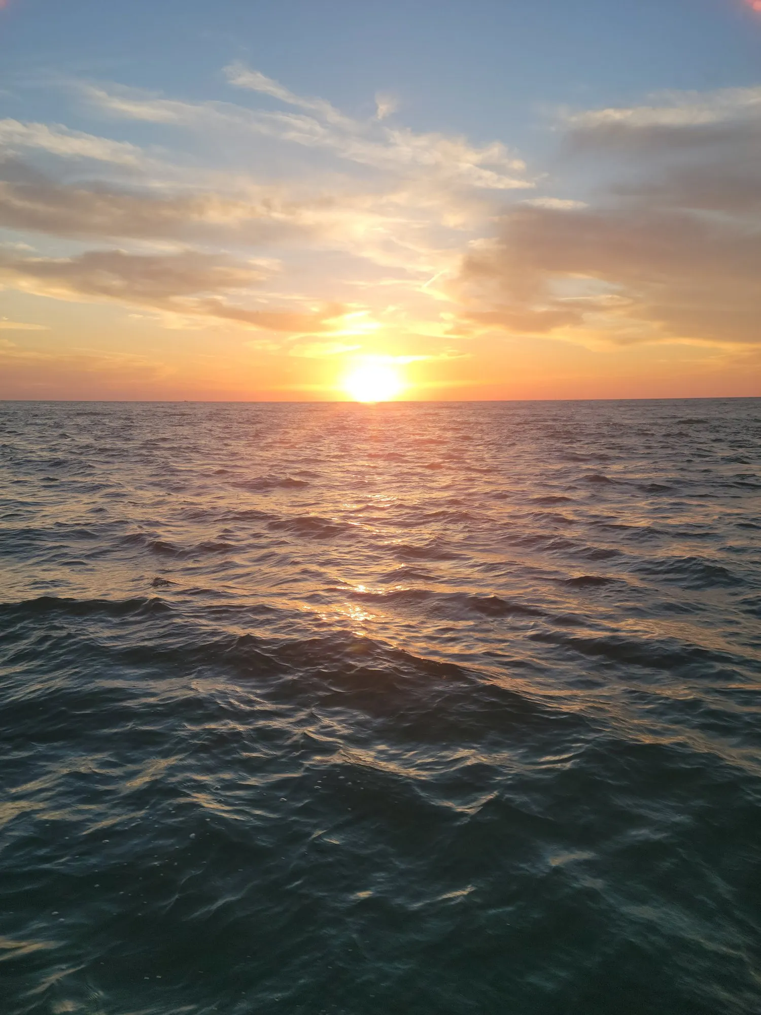 Golden sun above the horizon over open Gulf water at sunset
