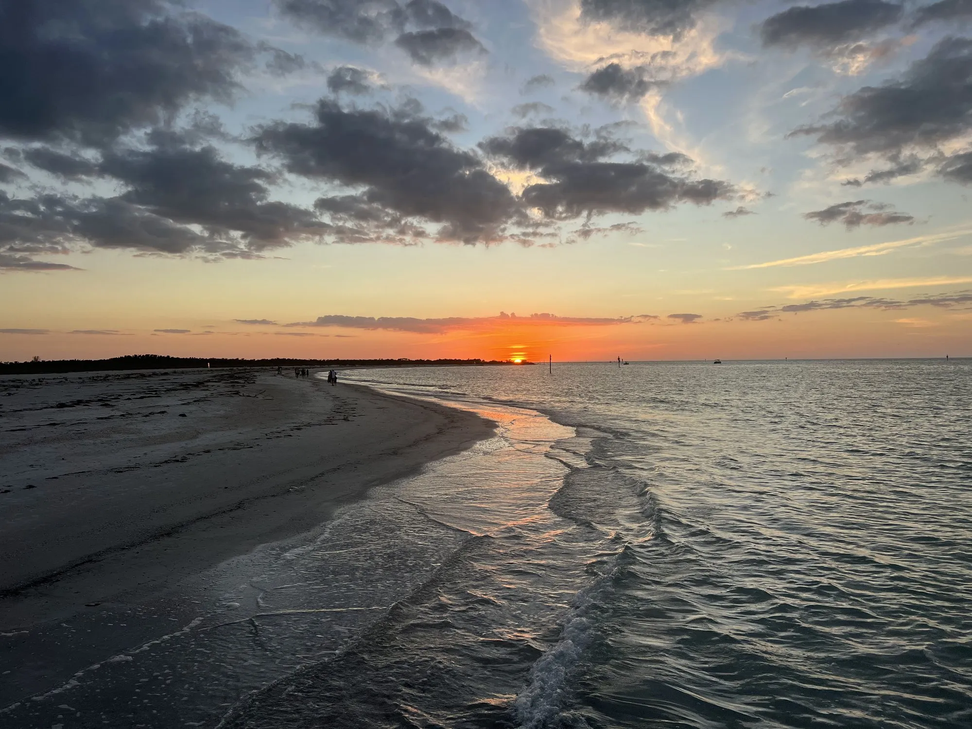 Orange sun setting over the Gulf from a quiet beach shoreline